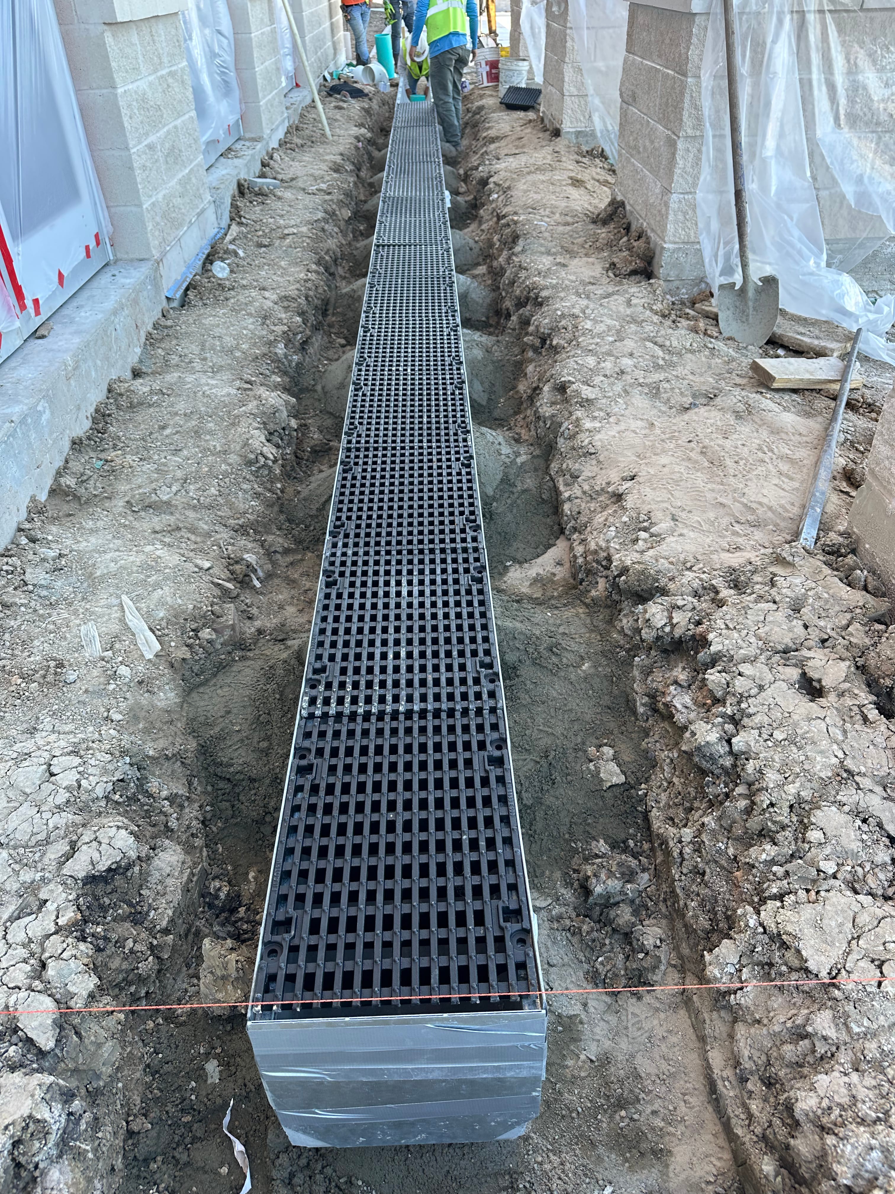 Storm drainage system installation in a trench between building foundations